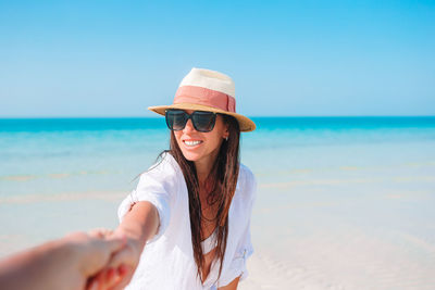 Young woman wearing sunglasses on beach against sky