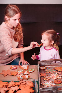 Girl feeding sister with cookies