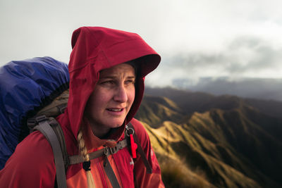 Woman with backpack looking away while standing on mountain