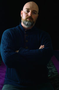 Portrait of young man standing against black background