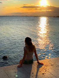 Woman standing on beach against sky during sunset