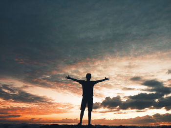 Rear view of silhouette man standing against sky during sunset