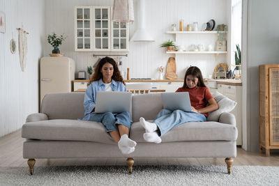 Woman using laptop while sitting on sofa at home