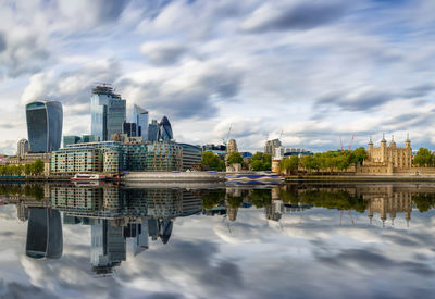 Reflection of buildings on lake against cloudy sky