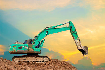 Crane at construction site against sky during sunset