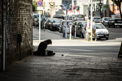 Side view of beggar sitting on city street