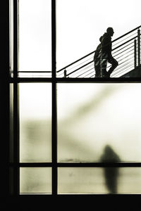 Silhouette man walking on bridge