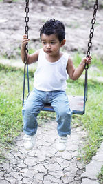 Portrait of boy sitting on swing at playground