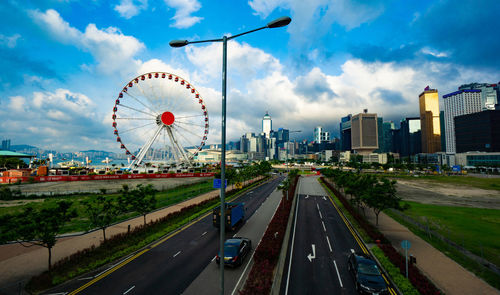 Ferris wheel by city buildings against sky