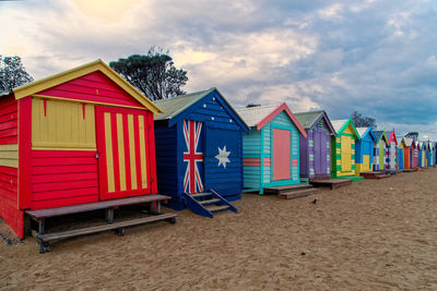 Multi colored huts on beach against sky