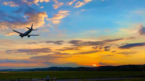 Low angle view of silhouette airplane flying against sky during sunset