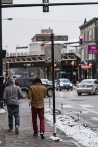 Rear view of people walking on city street in winter