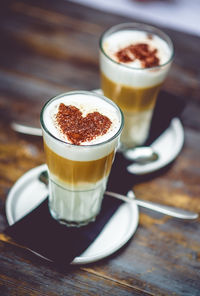 High angle view of chocolate hearts made on cappuccino served on wooden table