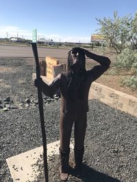 Man standing by sculpture against sky in city