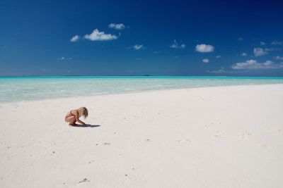 View of girl playing on beach against blue sky