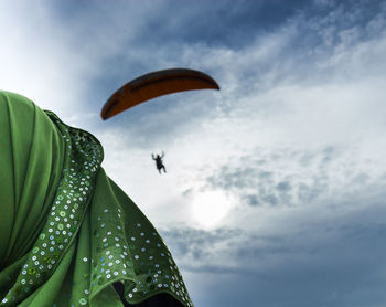 Close-up of woman looking at person paragliding in sky