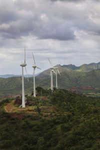 Wind turbines on field against sky