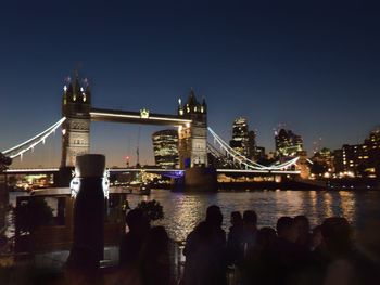 Illuminated bridge over river against sky at night