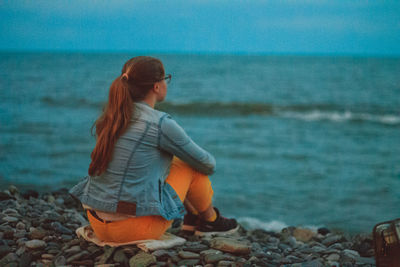 Rear view of young woman standing at beach