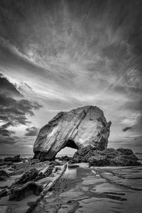 Rock formation on beach against sky