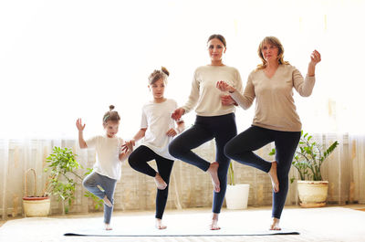 Full length of family doing yoga at home