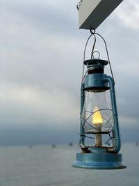 Lantern hanging over sea against sky
