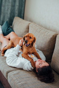 High angle view of woman with dog lying down on sofa at home