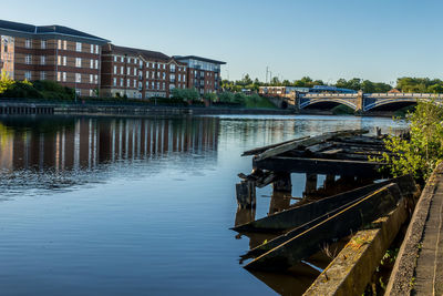 Bridge over river by buildings against sky