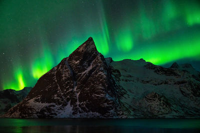 Scenic view of aurora borealis over snowcapped mountains at night