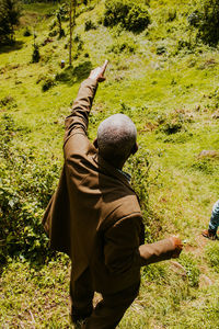 Rear view of man with arms raised on field