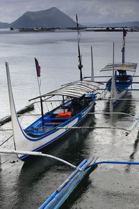 Fishing boats moored on sea against sky