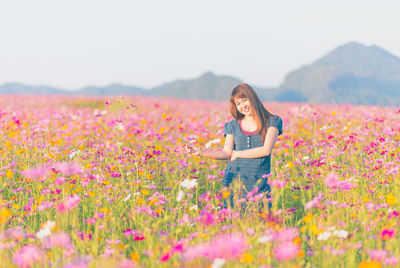 Portrait of smiling woman standing amidst blooming flowers