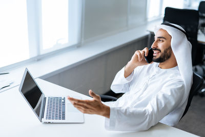 Midsection of doctor using mobile phone while sitting on table