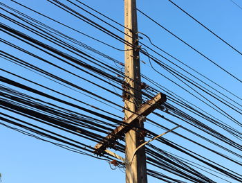 Low angle view of electricity pylon against blue sky