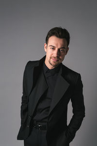 Portrait of young man standing against gray background