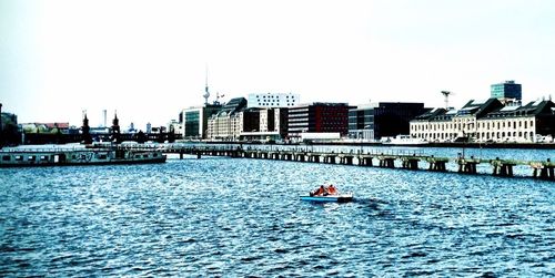 Boats in river with city in background