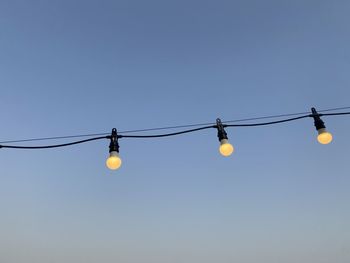 Low angle view of light bulbs against clear sky