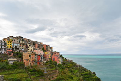 Buildings by sea against sky