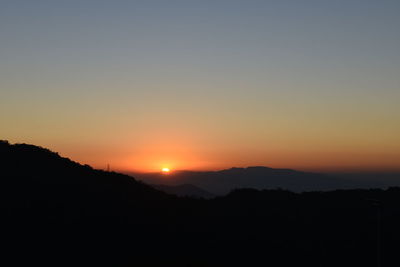 Scenic view of silhouette mountains against orange sky