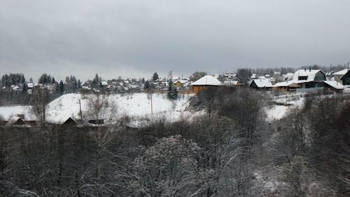 Buildings by river against sky during winter