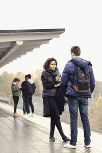 Couple talking on subway platform while friends standing in background