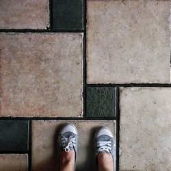 Low section of man standing on tiled floor