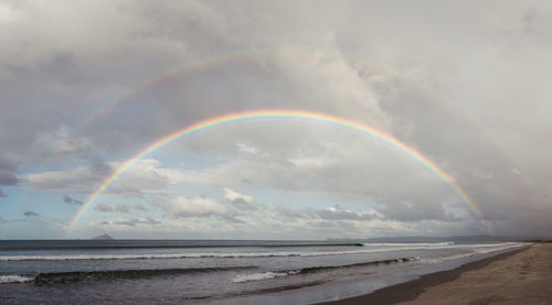 Scenic view of rainbow over sea against sky