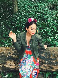 Young woman standing against plants