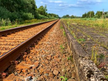 Surface level of railroad tracks on field against sky