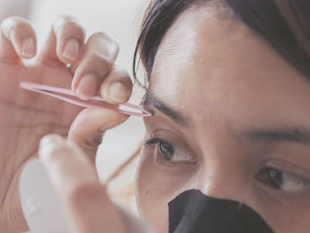 Close-up of woman removing eyebrows