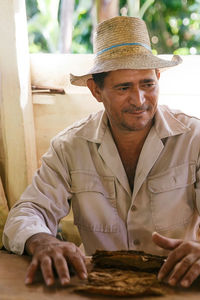 Man wearing hat making tobacco product on table