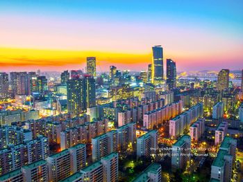 Aerial view of illuminated cityscape against sky at sunset