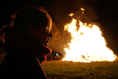 Close-up of woman looking away by fire at night
