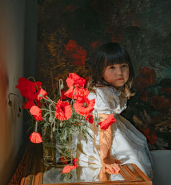 Portrait of girl standing against red wall